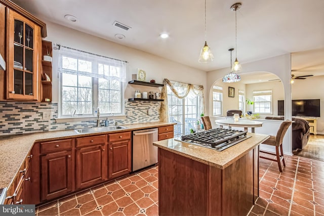 kitchen with decorative light fixtures, tasteful backsplash, sink, light stone counters, and stainless steel appliances