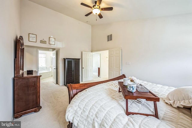 bedroom with ceiling fan, light colored carpet, ensuite bathroom, and high vaulted ceiling