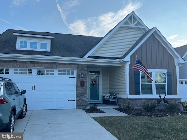 view of front of property with a garage, driveway, a shingled roof, and stone siding