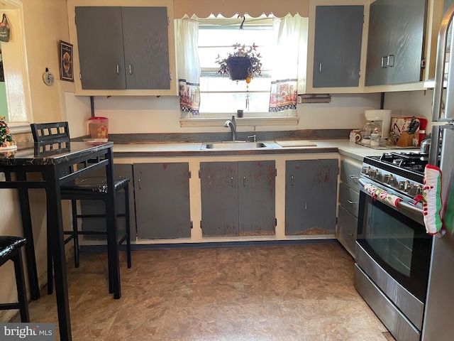 kitchen featuring stainless steel range with gas stovetop, sink, and gray cabinetry