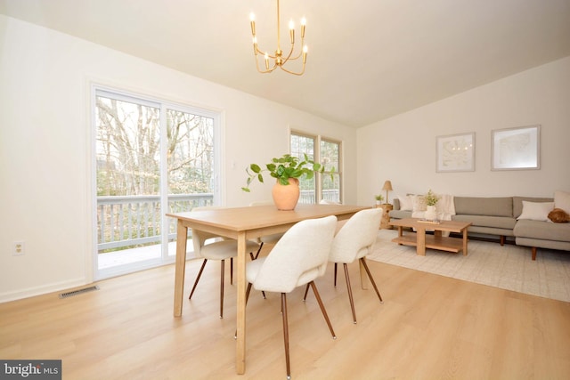 dining area featuring vaulted ceiling, plenty of natural light, and light hardwood / wood-style flooring