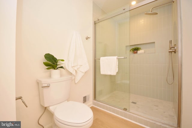 bathroom featuring toilet and a shower with door