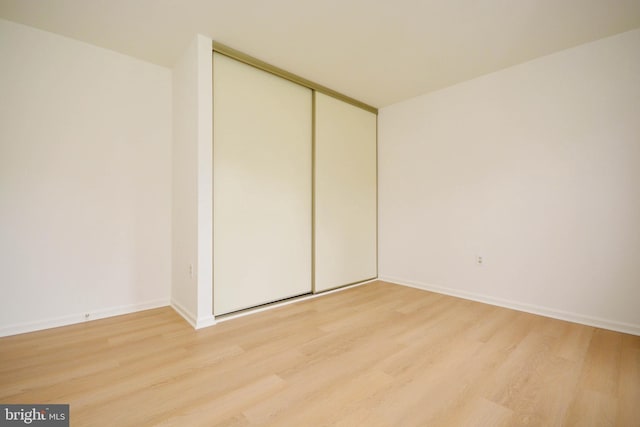 unfurnished bedroom featuring light hardwood / wood-style flooring and a closet