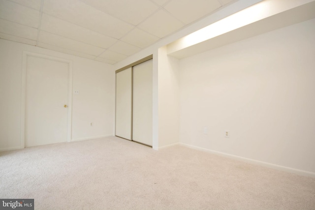 interior space with a paneled ceiling, light colored carpet, and a closet