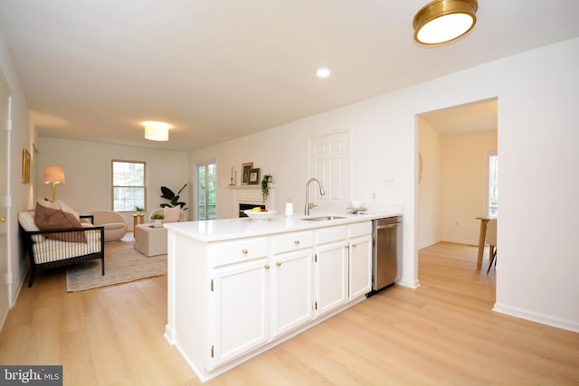 kitchen featuring white cabinetry, stainless steel dishwasher, sink, and light hardwood / wood-style flooring