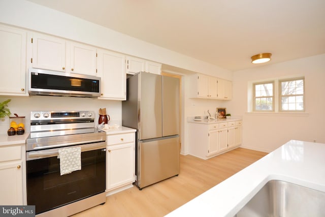 kitchen featuring white cabinetry, appliances with stainless steel finishes, and light hardwood / wood-style flooring