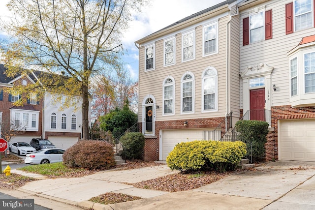 townhome / multi-family property with concrete driveway, brick siding, and an attached garage