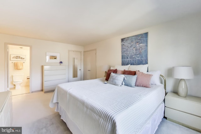 bedroom with connected bathroom and light colored carpet