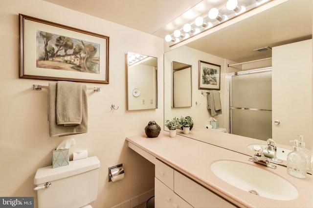 bathroom with vanity, toilet, and a shower with door