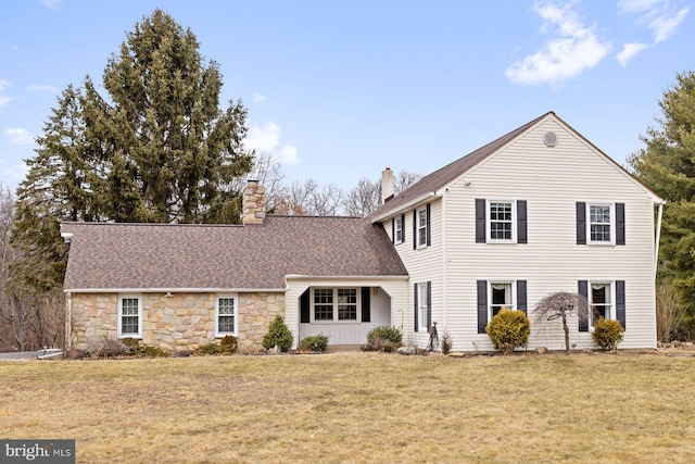 traditional-style house featuring a shingled roof, a front yard, and a chimney