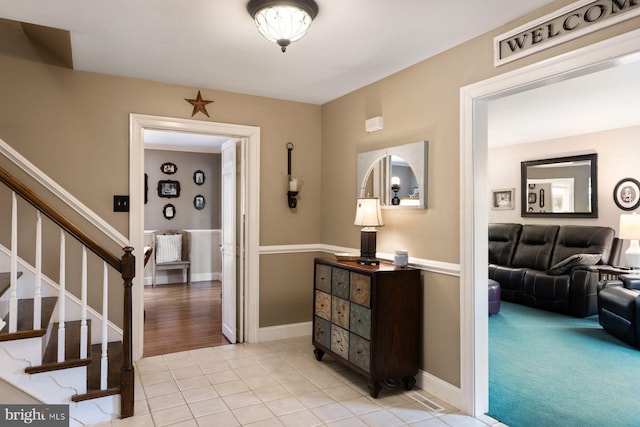 foyer with stairway, light tile patterned flooring, and baseboards