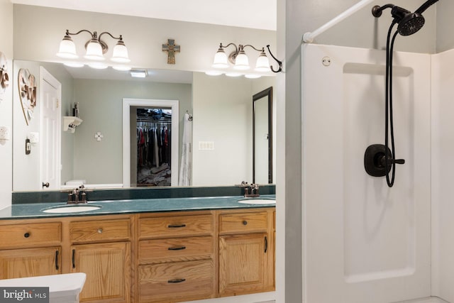 full bathroom featuring double vanity, a walk in closet, and a sink