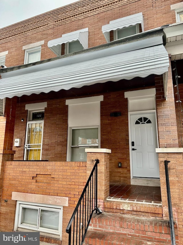 entrance to property with brick siding and a porch