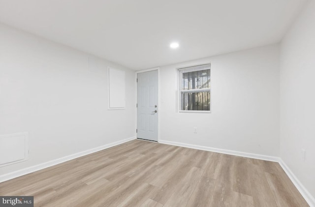 spare room featuring baseboards and light wood finished floors