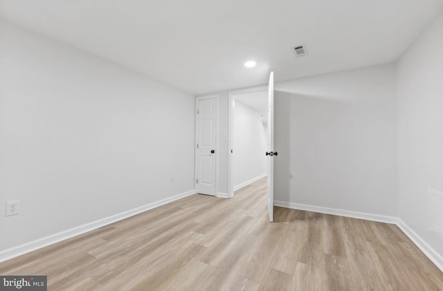 empty room featuring light wood-style floors, baseboards, and visible vents