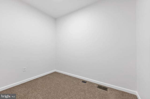 empty room with carpet flooring, visible vents, and baseboards