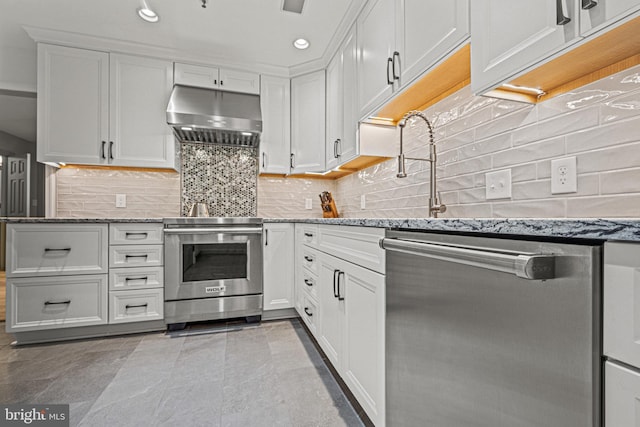 kitchen with white cabinets, appliances with stainless steel finishes, light stone countertops, and under cabinet range hood