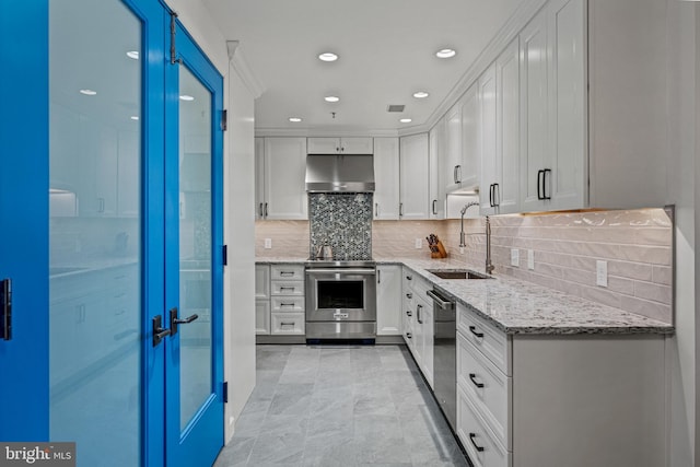 kitchen featuring appliances with stainless steel finishes, white cabinets, a sink, light stone countertops, and under cabinet range hood