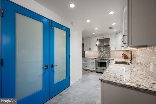 kitchen featuring white cabinets, high end stainless steel range, light stone countertops, under cabinet range hood, and a sink