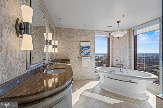 bathroom with a freestanding bath, a healthy amount of sunlight, visible vents, and wallpapered walls