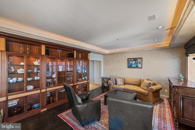 living room featuring a raised ceiling, wood finished floors, and visible vents