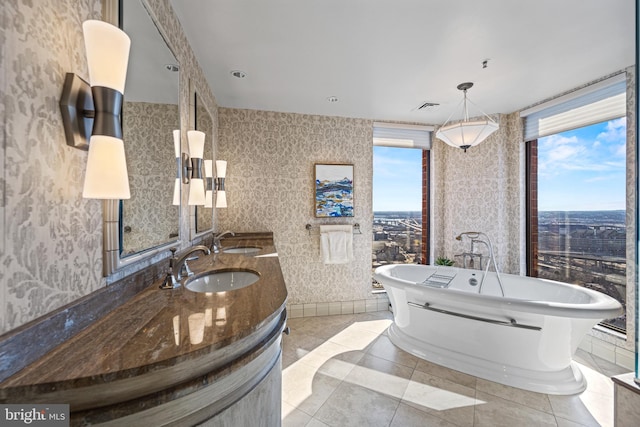 full bath with wallpapered walls, plenty of natural light, visible vents, and a sink