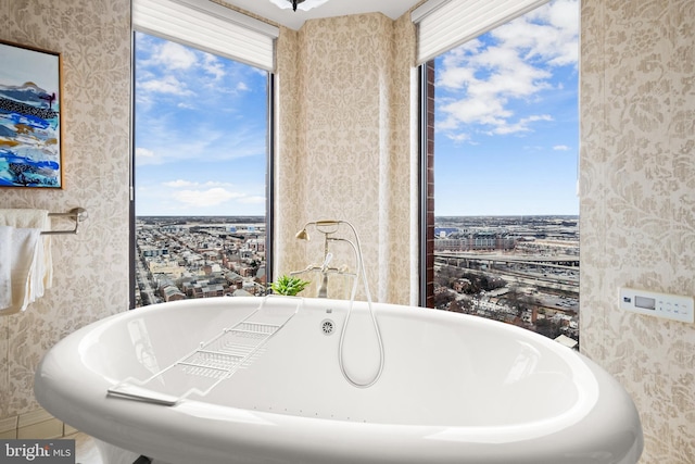 full bath featuring a soaking tub and wallpapered walls