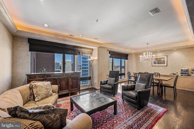 living area with dark wood-type flooring, visible vents, baseboards, a raised ceiling, and an inviting chandelier