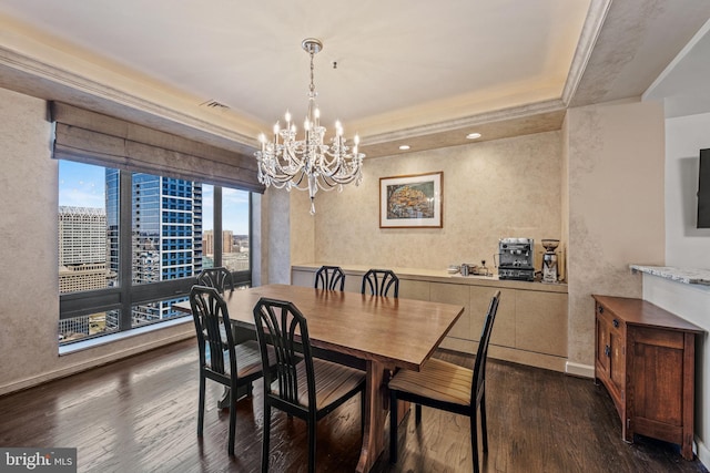 dining room with a tray ceiling, dark wood finished floors, visible vents, an inviting chandelier, and baseboards