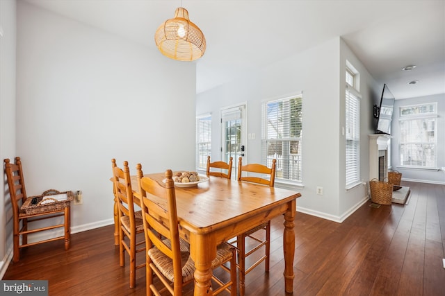 dining room featuring baseboards, hardwood / wood-style floors, and a fireplace