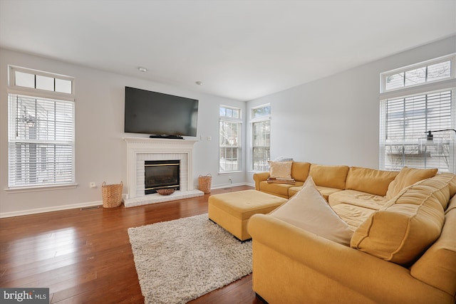 living room featuring a wealth of natural light, baseboards, a fireplace, and dark wood-style flooring