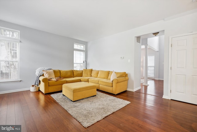 living area with dark wood finished floors, visible vents, baseboards, and ornate columns