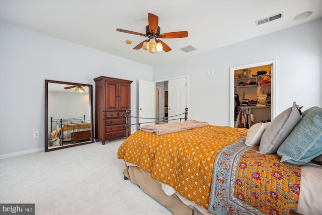 bedroom with a spacious closet, light colored carpet, visible vents, and a closet