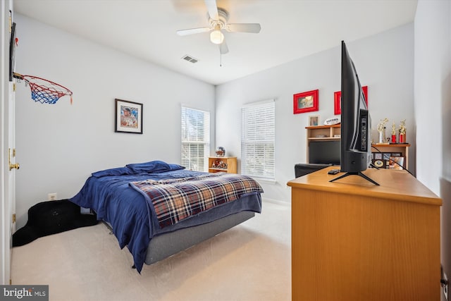 bedroom featuring a ceiling fan, visible vents, and light carpet