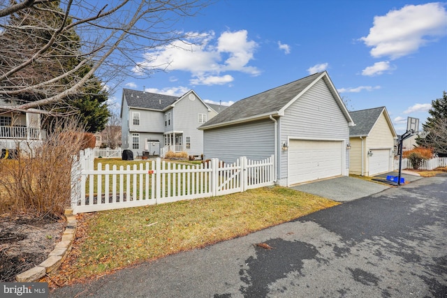 view of side of property with a fenced front yard, an outdoor structure, a garage, and roof with shingles