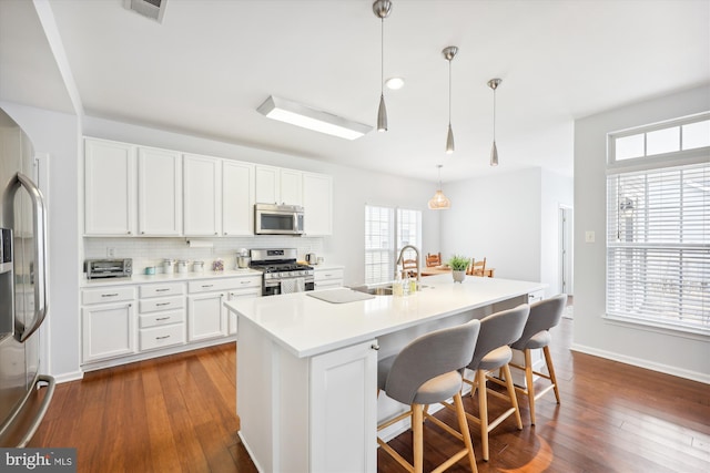 kitchen with a sink, decorative backsplash, appliances with stainless steel finishes, and white cabinetry