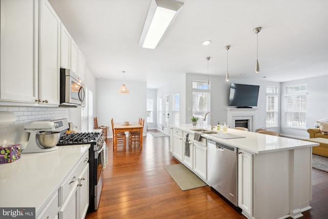 kitchen featuring dark wood finished floors, a sink, decorative backsplash, stainless steel appliances, and open floor plan