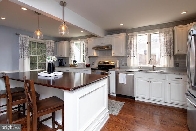 kitchen featuring sink, a breakfast bar, stainless steel appliances, white cabinets, and a kitchen island