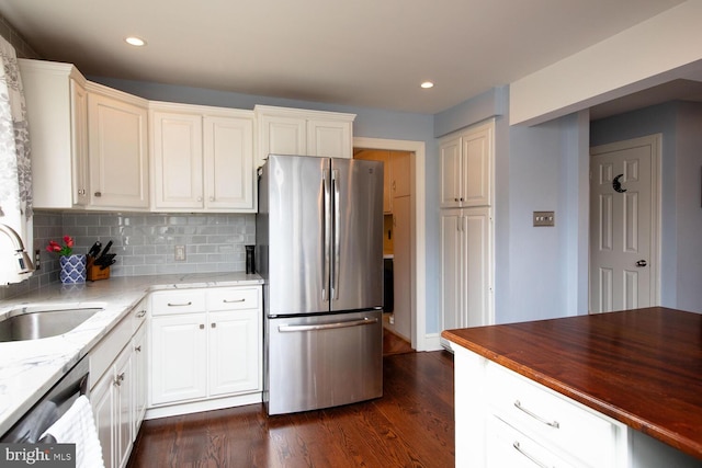 kitchen with sink, dark stone counters, dark hardwood / wood-style floors, stainless steel appliances, and backsplash