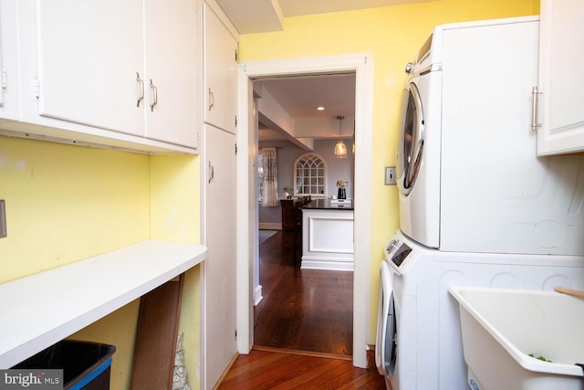 laundry room featuring cabinets, stacked washer and clothes dryer, dark hardwood / wood-style flooring, and sink