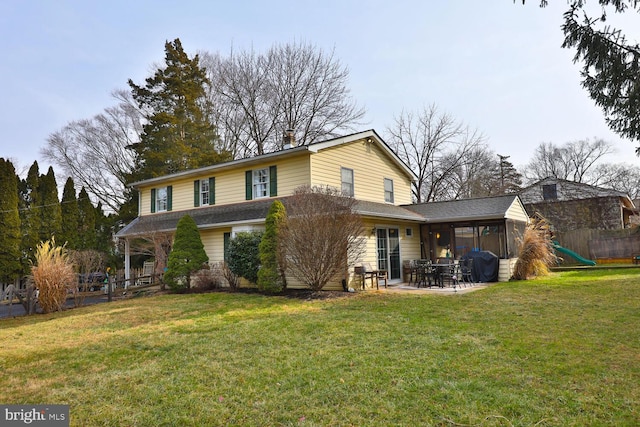 rear view of property with a lawn, a sunroom, and a patio