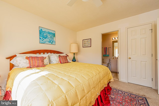 bedroom with ceiling fan, ensuite bathroom, a textured ceiling, and carpet