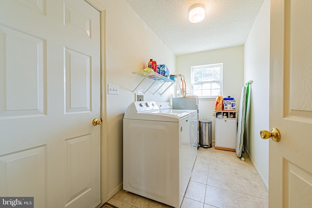 clothes washing area with light tile patterned floors, washer and dryer, and a textured ceiling