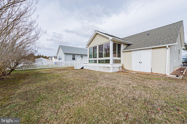 rear view of house with a yard and a sunroom