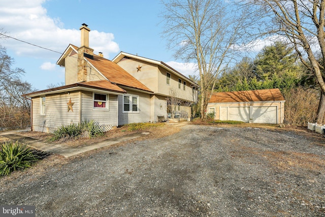 view of side of home featuring a garage and an outbuilding