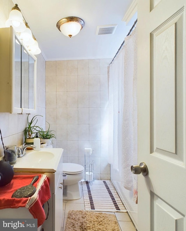 bathroom featuring tile walls, visible vents, toilet, vanity, and tile patterned floors