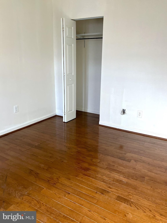 unfurnished bedroom with a closet, baseboards, and wood finished floors