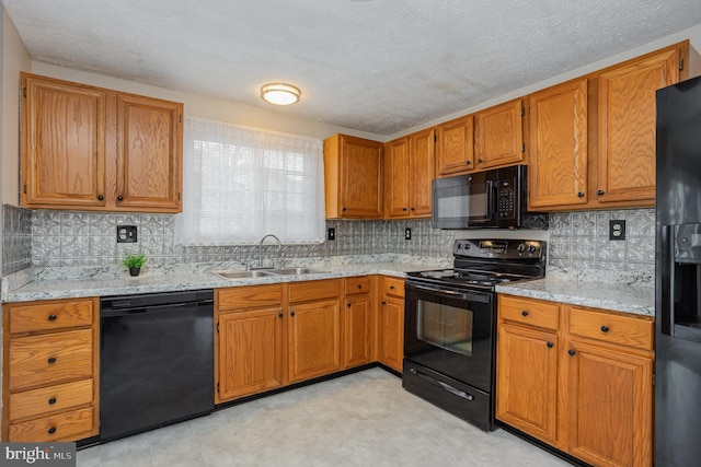 kitchen with sink, light stone counters, black appliances, a textured ceiling, and backsplash