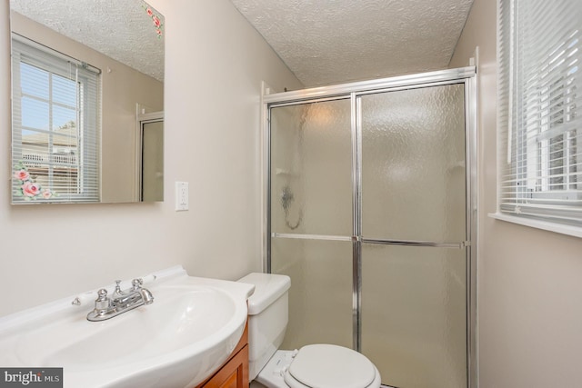 bathroom with a shower with door, vanity, a textured ceiling, and toilet