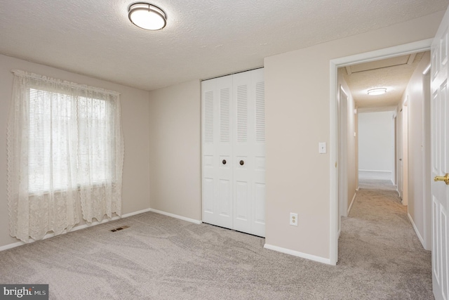 unfurnished bedroom with light carpet, a closet, and a textured ceiling